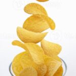 Descargar Patatas fritas cayendo en un recipiente de vidrio aislado sobre fondo blanco_ gratis